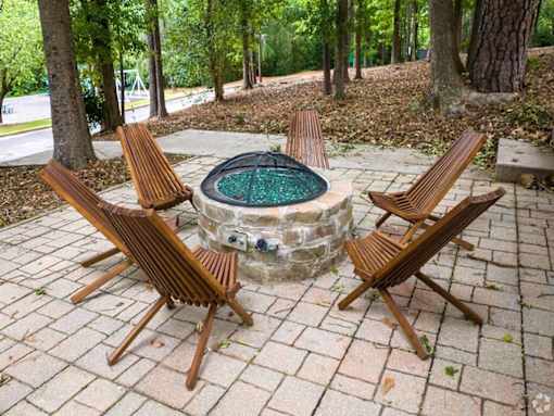 a stone fire pit with wooden chairs around it